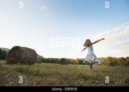 New York state USA field hay bales girl dancing arms outstretched Stock Photo