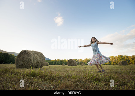 New York state USA field hay bales girl dancing arms outstretched Stock Photo