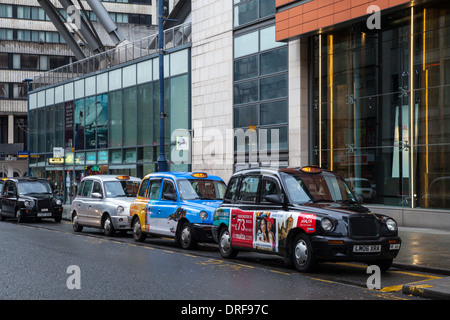 Colourful Taxis parked in St Mary's Gate Hackney Cabs, Private Hire Vehicles in Manchester City Centre, Lancashire, UK Stock Photo