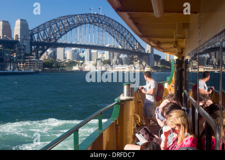 Passengers on deck of ferry leaving Circular Quay passing Sydney Harbour Bridge Sydney New South Wales NSW Australia Stock Photo