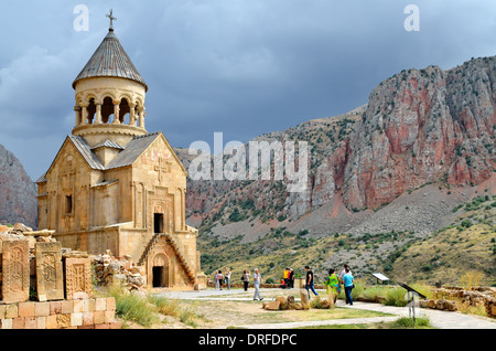 Khachkars and Surp Astvatsatsin, the Holy Mother of God church, with red cliffs in the background, Noravank monastery, Armenia Stock Photo