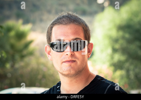 Portrait of a young man with sunglasses over green natural background. Stock Photo