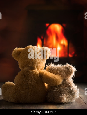 Two teddy bears sitting by the fire Stock Photo