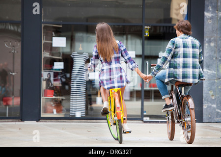 Young couple riding bicycles together, holding hands, Osijek, Croatia Stock Photo