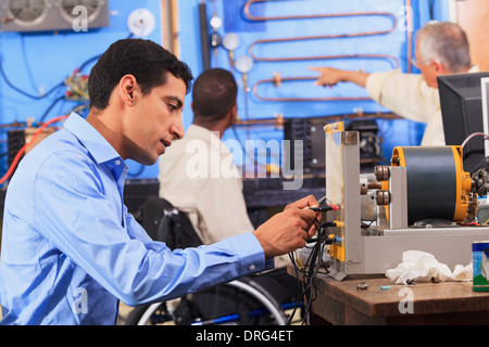 Student setting up generator experiment while instructor discusses HVAC system to student in wheelchair Stock Photo