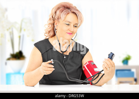 Middle aged woman measuring blood pressure at home Stock Photo