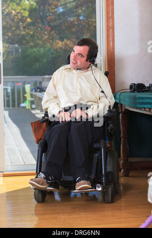 Man with Cerebral Palsy in motorized wheelchair using his earphones Stock Photo