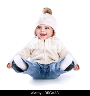 Little baby having fun in the studio isolated on white background, sitting on the floor with legs up, wearing warm stylish hat Stock Photo