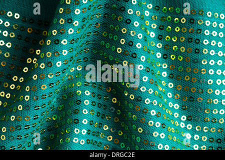 Green shiny sequine background texture abstract cloth wavy folds. Elegant sequined sparkling textile close up Stock Photo