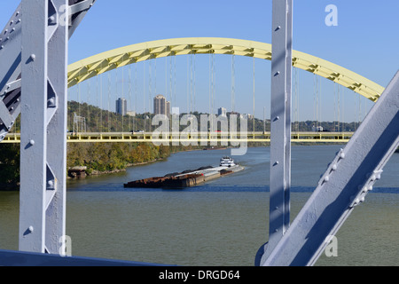 A barge loaded with recycling materials and coal passes the bridges on the Ohio River between Cincinnati, OH and Covington, KY. Stock Photo