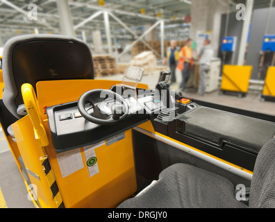 Parked forklift in an industry warehouse, workers and shelves in the background Stock Photo