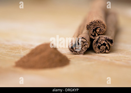 Cinnamon sticks and ground cinnamon on a wooden board. Stock Photo