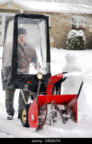 Man uisng snowblower in his home entryway during a winter blizzard Stock Photo