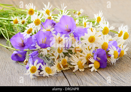 Campanula and chamomile flowers on wooden table Stock Photo