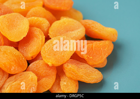 Pile of orange color dried apricots on blue plate, fruit background Stock Photo