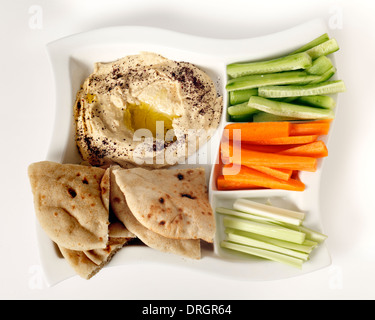 Top view of a dip tray with hummus, bread, carrot sticks, celery and cucumber. Stock Photo