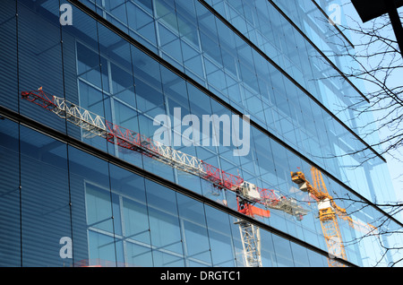 two cranes are reflected in a glass wall of a building Stock Photo