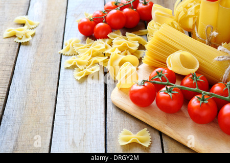 uncooked pasta and cherry tomatoes branch, food closeup Stock Photo