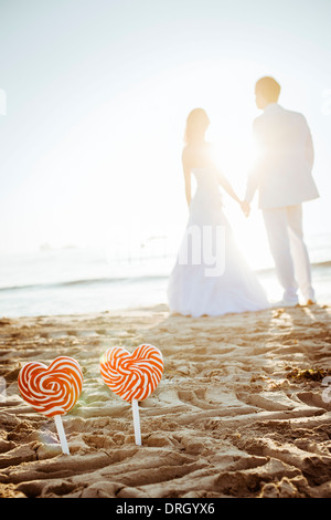 Brautpaar mit Herzlutschern am Strand auf Ibiza, Spanien - bridal couple with heart lollies at the Beach, Ibiza, Spain Stock Photo