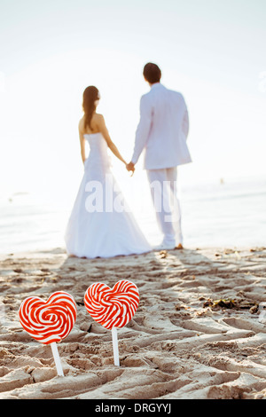 Brautpaar mit Herzlutschern am Strand auf Ibiza, Spanien - bridal couple with heart lollies at the Beach, Ibiza, Spain Stock Photo