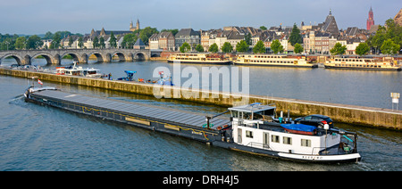 Maastricht & Saint Servatius arched bridge early morning loaded motor barge with car on deck River Meuse in dedicated commercial waterway channel EU Stock Photo