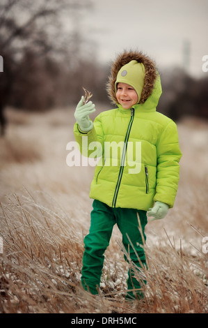 boy in a green suit walks in the park in winter with frozen trees and grass Stock Photo
