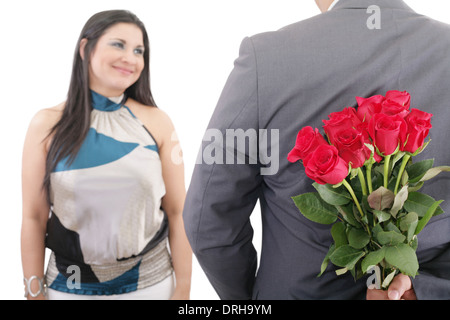 man hiding bunch of red roses behind his back to surprise his girlfriend Stock Photo