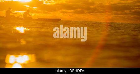 silhouette of two one man canoes paddling off Waikiki Beach at sunset. Stock Photo