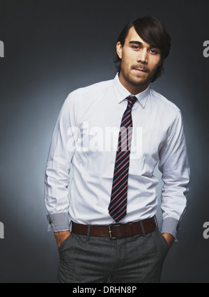 Confident young male executive standing with his hands in pocket. Young businessman looking at camera. Stock Photo