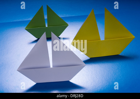 Group of Paper Boats Sailing on Blue paper sea. Origami Ship Stock Photo
