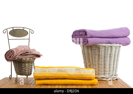Wicker baskets full of clean colored towels on a wooden table, on white background Stock Photo