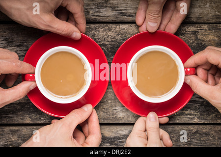 Hands Taking Two Red Cups of Coffee on old Wood Background Stock Photo