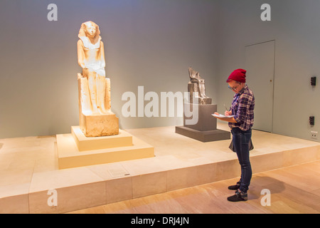 A college student examining a sculpture in an art museum for a college course in the university. Stock Photo