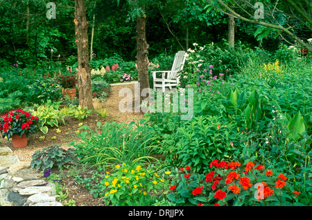 Shaded garden path with blooming flowers and white Adirondack chair, Missouri, USA Stock Photo