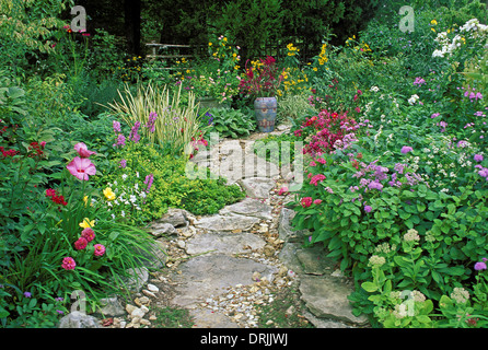 Path in garden with painted Mexican ceramic vase and blooming flowers in backyard garden, Missouri USA Stock Photo