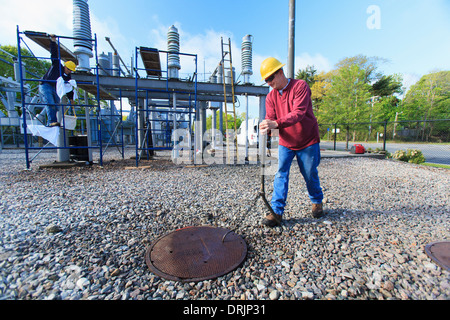 Power engineer accessing manhole cover at high voltage power distribution station Stock Photo