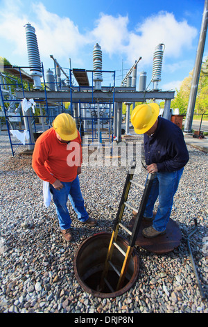 Power engineers looking inside manhole at high voltage power distribution station, Braintree, Massachusetts, USA Stock Photo