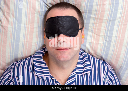 man sleeping with a mask on eyes Stock Photo