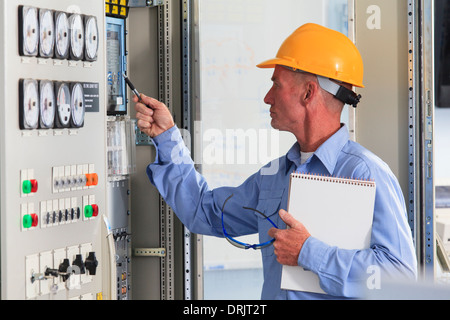 Electrical engineer inspecting power plant controls in central operations room of power plant Stock Photo