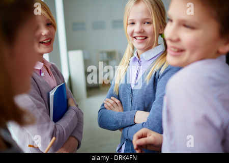 Portrait of three happy schoolgirls and schoolboy talking during school break Stock Photo