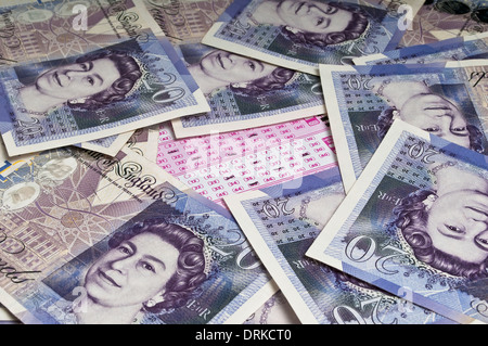 Marked lottery ticket in the middle of a pile of scattered twenty pound notes Stock Photo