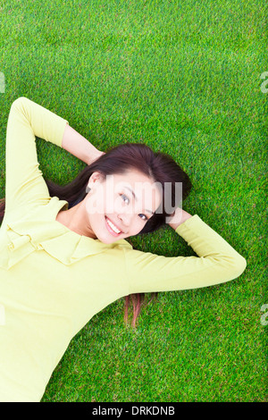 beautiful young woman laying down on grassland in park Stock Photo