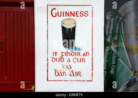 An retro advert for Guinness, painted on a pub wall in Galway, Ireland. Also shows part of a poster for the Heineken Cup. Stock Photo