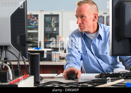 Electrical engineer using computer mouse while monitoring operations at a power plant Stock Photo