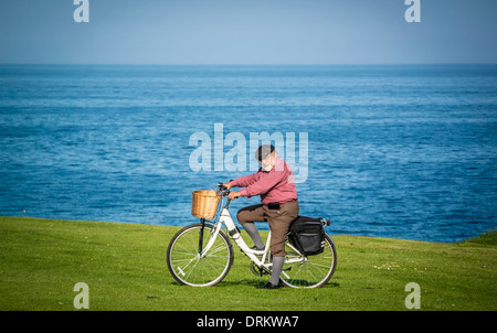 Elderly caucasian man dressed in plus four trousers on a traditional ladies bicycle, on the seafront at Whitley Bay, Tyne and Wear. Stock Photo