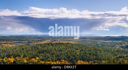 A storm cloud receding over an expansive view of fall foliage in Killarney Provincial Park, Ontario, Canada. Stock Photo