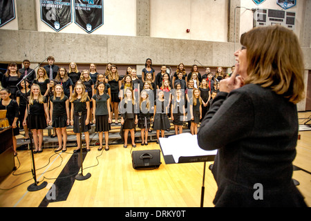 A music teacher directs multiracial middle school children singing Christmas carols as a group at a school concert in Aliso Viejo, CA Stock Photo