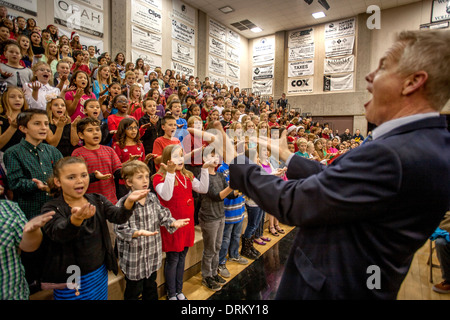 A music teacher directs multiracial middle school children singing Christmas carols as a group at a school concert in Aliso Viejo, CA Stock Photo