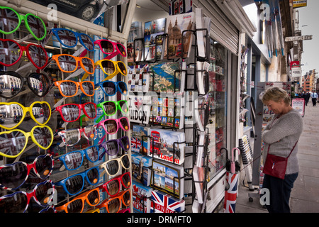 a tourist looking at various souvenirs displayed outside of a shop in London, UK Stock Photo