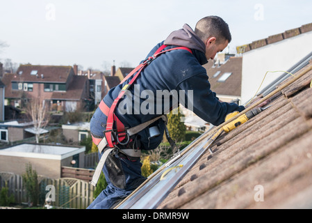 man making the construction for the solar panels high on the roof Stock Photo